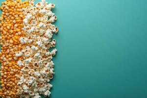 Popcorn and corn kernels forming a border on a teal background photo