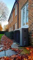 Air source heat pump installed outside a brick house during autumn photo
