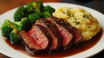 Sliced roast beef with mashed potatoes and broccoli on plate photo