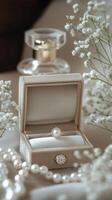 Elegant pearl ring resting in open jewelry box near perfume and gypsophila flowers photo