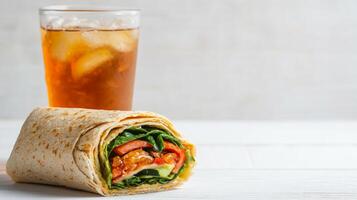 Healthy Lunch Break with Fresh Veggie Wrap and Iced Tea on a White Wooden Table photo