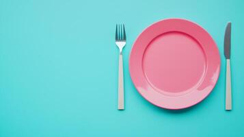 Elegant Dinner Setting with Pink Plate, Fork, and Knife on a Vibrant Turquoise Background photo