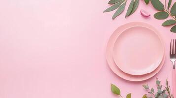 Elegant Dinner Concept with Pink Plates, Greenery, and Fork on Pastel Pink Background photo