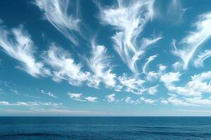 Serene Ocean Horizon with Wispy Cloud Patterns Against Clear Blue Sky photo