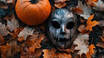 festive arrangement showcases a scary mask and a bright orange pumpkin resting on a bed of vibrant autumn leaves creating a perfect Halloween atmosphere. photo
