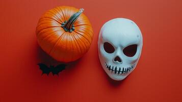 vibrant red background showcases a flat lay arrangement of a scary mask a bright orange pumpkin and decorative bat accents perfect for Halloween celebrations. photo