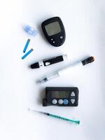 Diabetes management toolkit, glucose monitors, insulin pens, test strips, and syringe on white background photo