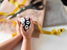 Hands holding sewing threads with scissors and measuring tape in tailoring setup photo
