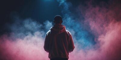 A man in a hoodie standing in front of a smoke cloud photo