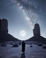 A man standing in the desert with the milky in the background photo