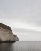 A white cliff on the ocean with a boat in the distance photo