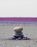 A stack of stones on a beach with purple water photo