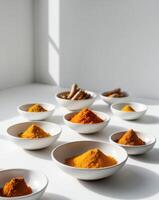 A variety of spices in bowls on a white table photo