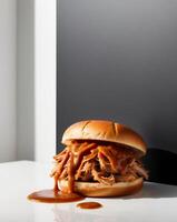 A pulled pork sandwich with sauce on a white table photo