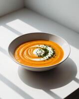 A bowl of carrot soup with sour cream photo