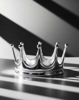 A silver crown sits on a table in front of a window photo