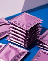 Stack of Individual Pink Foil Packets on a Blue Background. photo
