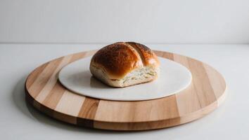 Wooden board featuring delicious poppy seed bun on white surface viewed up close. photo