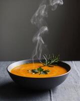 Steaming Hot Bowl of Butternut Squash Soup Garnished with Fresh Herbs on Dark Background. photo