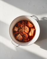 Kimchi Stew with Pork and Sesame Seeds in White Ceramic Pot. photo
