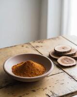Ground spice in clay bowl with dried wood slices on rustic wooden table. photo