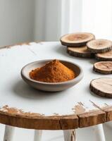Ground spice in clay bowl with dried wood slices on rustic wooden table. photo