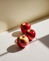 Three red apples on a white surface photo