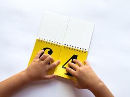 A child turns a page of learning numbers to the next number on a bright yellow background photo