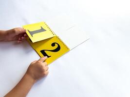 A child turns a page of learning numbers to the next number on a bright yellow background photo