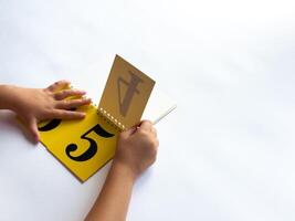 A child turns a page of learning numbers to the next number on a bright yellow background photo