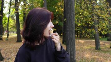 Teenage girl with striking looks playfully savors creamy ice cream cone in autumn park, tongue piercing adding hint of intrigue video