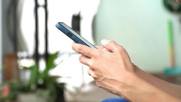 Woman hand holds a smartphone while typing a message, captured from a side view video