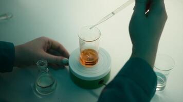 Scientist using a pipette to put solution in glass flask. Stock footage. Concept of medicine and chemistry. video