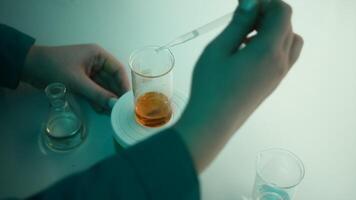Scientist using a pipette to put solution in glass flask. Stock footage. Concept of medicine and chemistry. video