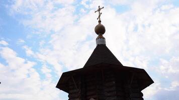 Ancient wooden tower of church. Media. Wooden tower of ancient church on background sky. Architecture of wooden church with cross on cloudy day video