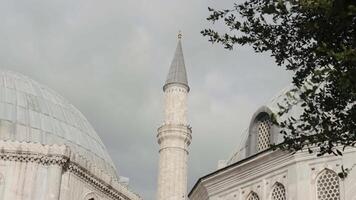 Minaret of a mosque on a cloudy sky background. Action. Summer green trees and mosque building. video