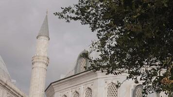 Minaret of a mosque on a cloudy sky background. Action. Summer green trees and mosque building. video