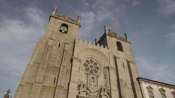 Portugal, Porto- July 29, 2022. Bottom view of ancient stone cathedral on background of sky. Action. Beautiful facade of ancient cathedral in Portugal. Se Cathedral in Porto video