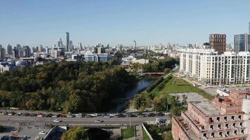 View of the built-up city from a height. Stock footage. A beautiful European city with high-rise buildings and offices and a river is visible over which cars are passing. video