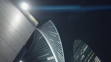 Bottom view of lantern and modern skyscrapers. Action. Bright street lamp on building on background of skyscrapers. Modern stylish high-rises at night video