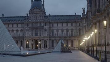 France, Paris - July 29, 2022. Beautiful pyramids of Louvre. Action. Beautiful square with glass pyramids of palace Museum in evening. Pyramids of Louvre Museum with evening lights video