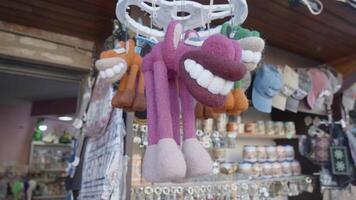An inexpensive market with souvenirs. Action. Displayed products with caps. with toy big teeth, dishes and key chains, taken from a close angle. video