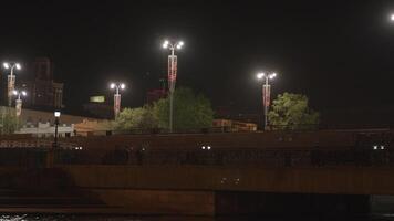 Evening city. Stock footage. A dark view of the city with a river over which there is a bridge with a road for tourists and new buildings surrounded by lanterns. video