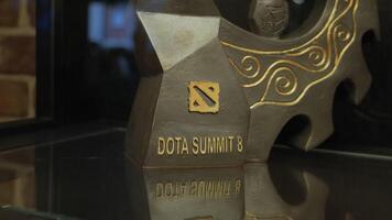 A museum exhibit of a game. Stock footage. A black figure with the designation DOTA 2 behind a fenced glass. Use only for editorial. video