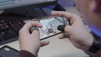 Close-up of man playing mobile game. Stock footage. Man with finger pads is playing on smartphone. Man professionally plays mobile games on smartphone video