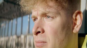 Close-up of young man on street with bright sunlight. Action. Young man looks into distance with sunlight. Portrait of man looking into distance and into camera video