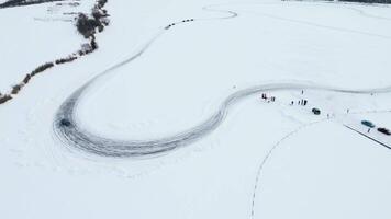 Aerial view of a frozen snow and ice covered lake with bending track. Clip. Drifting car on a winter day. video