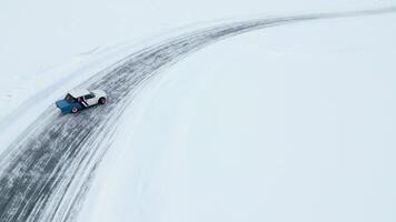 Aerial view of a frozen snow and ice covered lake with bending track. Clip. Drifting car on a winter day. video