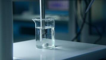 Rotating substance in glass of liquid in laboratory. Stock footage. Chemical experiment with substance and liquid in flask. Professional chemical experiment in laboratory video