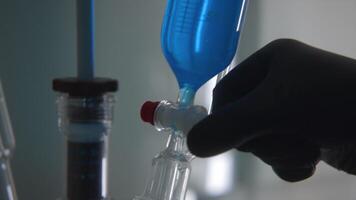 Close-up of working with chemicals in laboratory. Stock footage. Mixing of biochemical liquids for laboratory tests. Chemist mixes substances in flasks in laboratory video